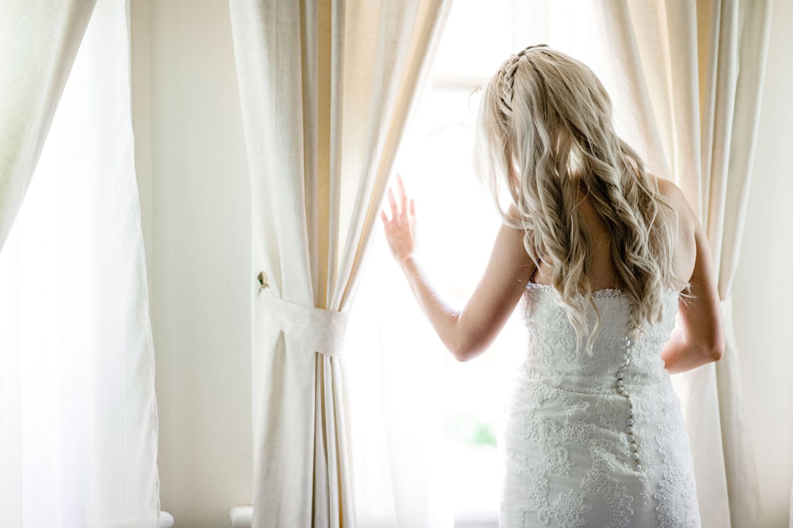 bride peering out the window before her Sydney family wedding