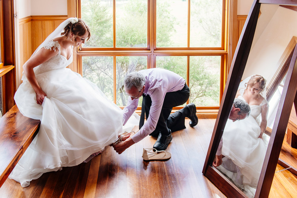 Father helping put his daughters wedding shoes on