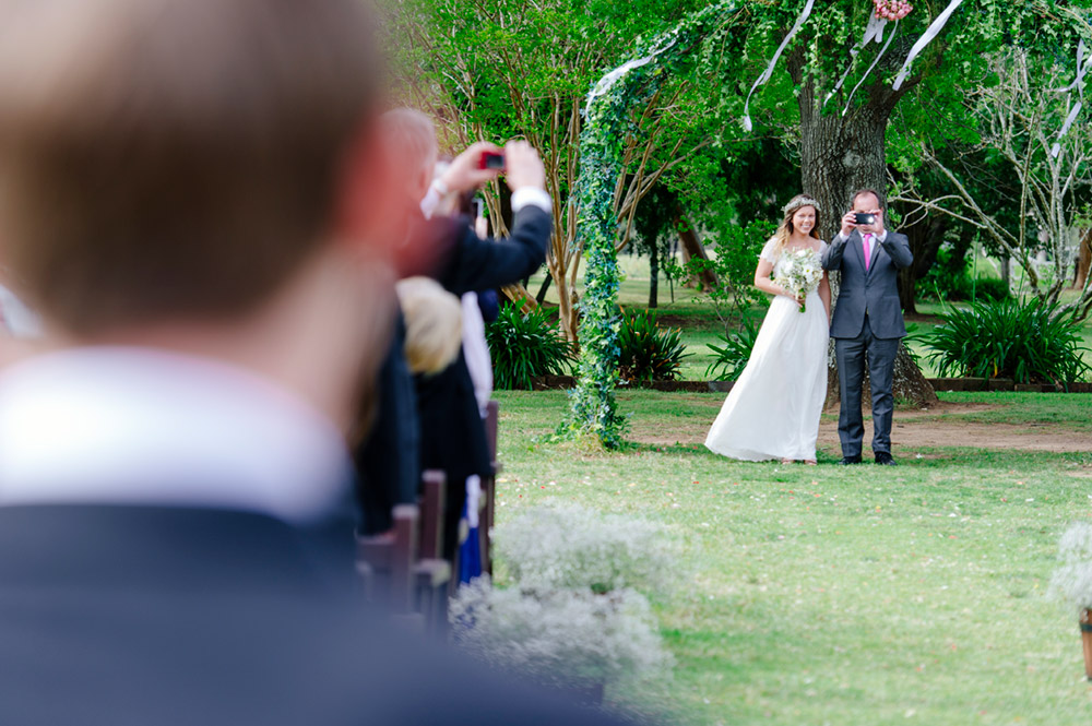 Father walking daughter down aisle stops to take a photo