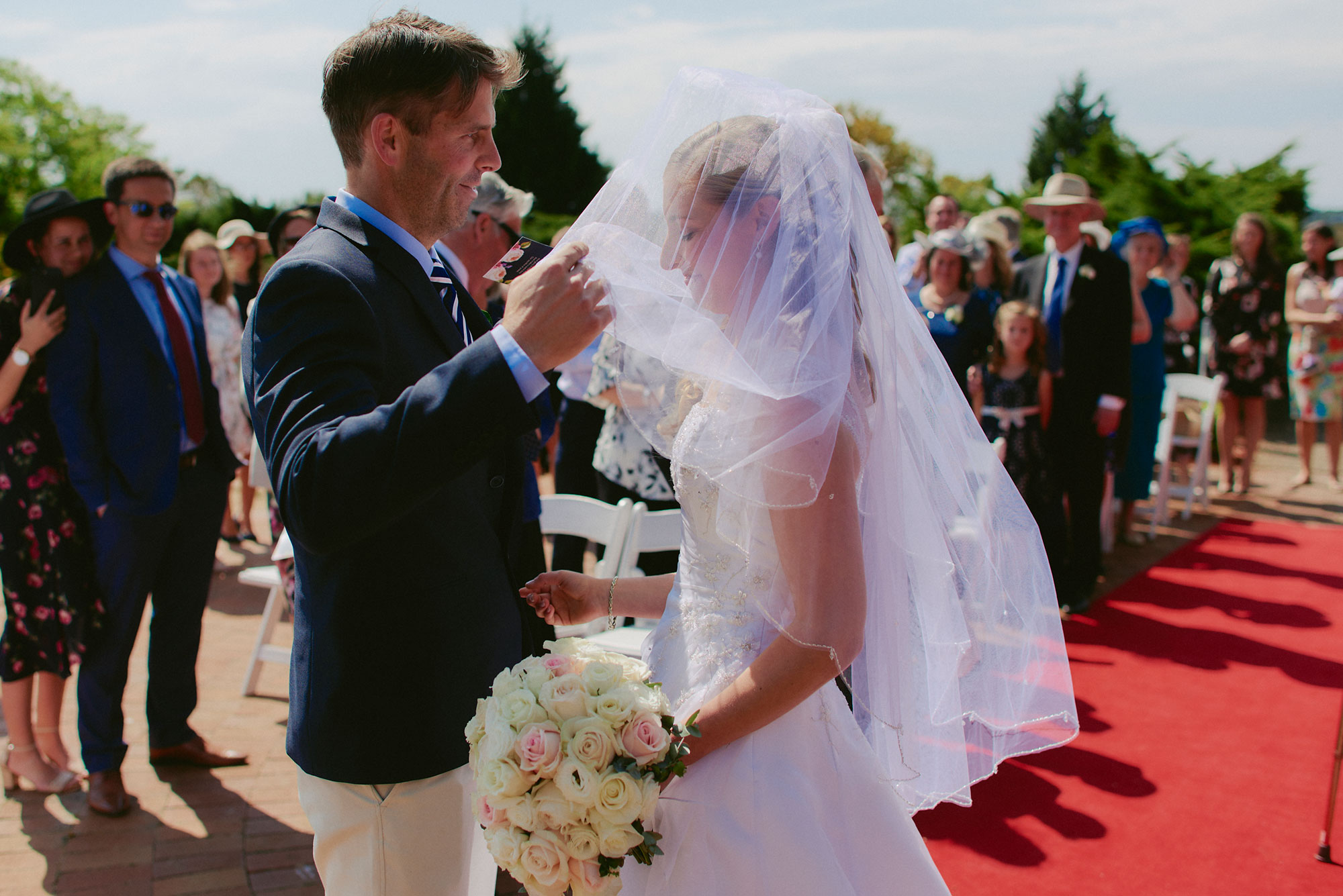 Groom lifting her bridal veil