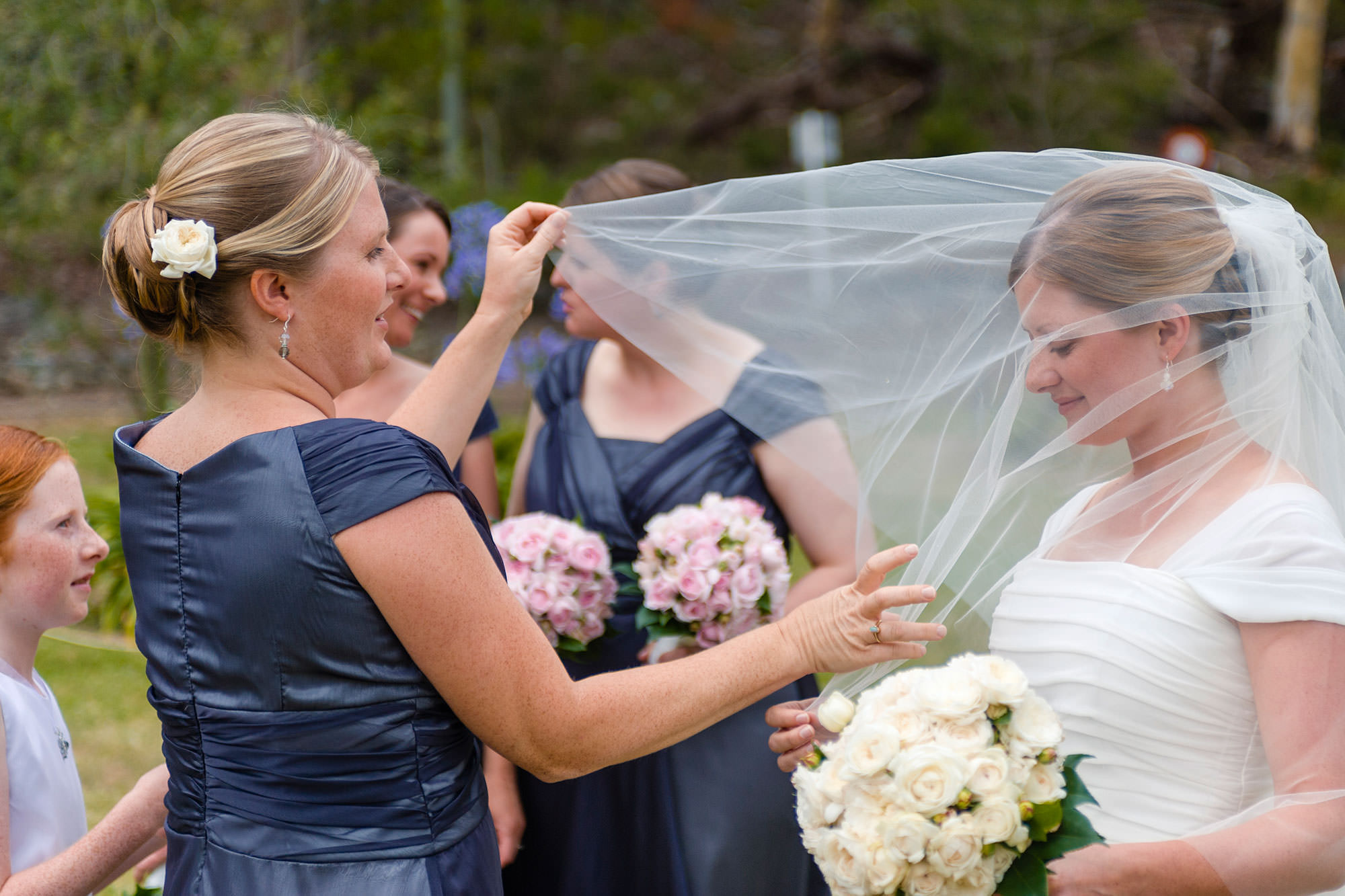 Bridesmaids adjusting veil