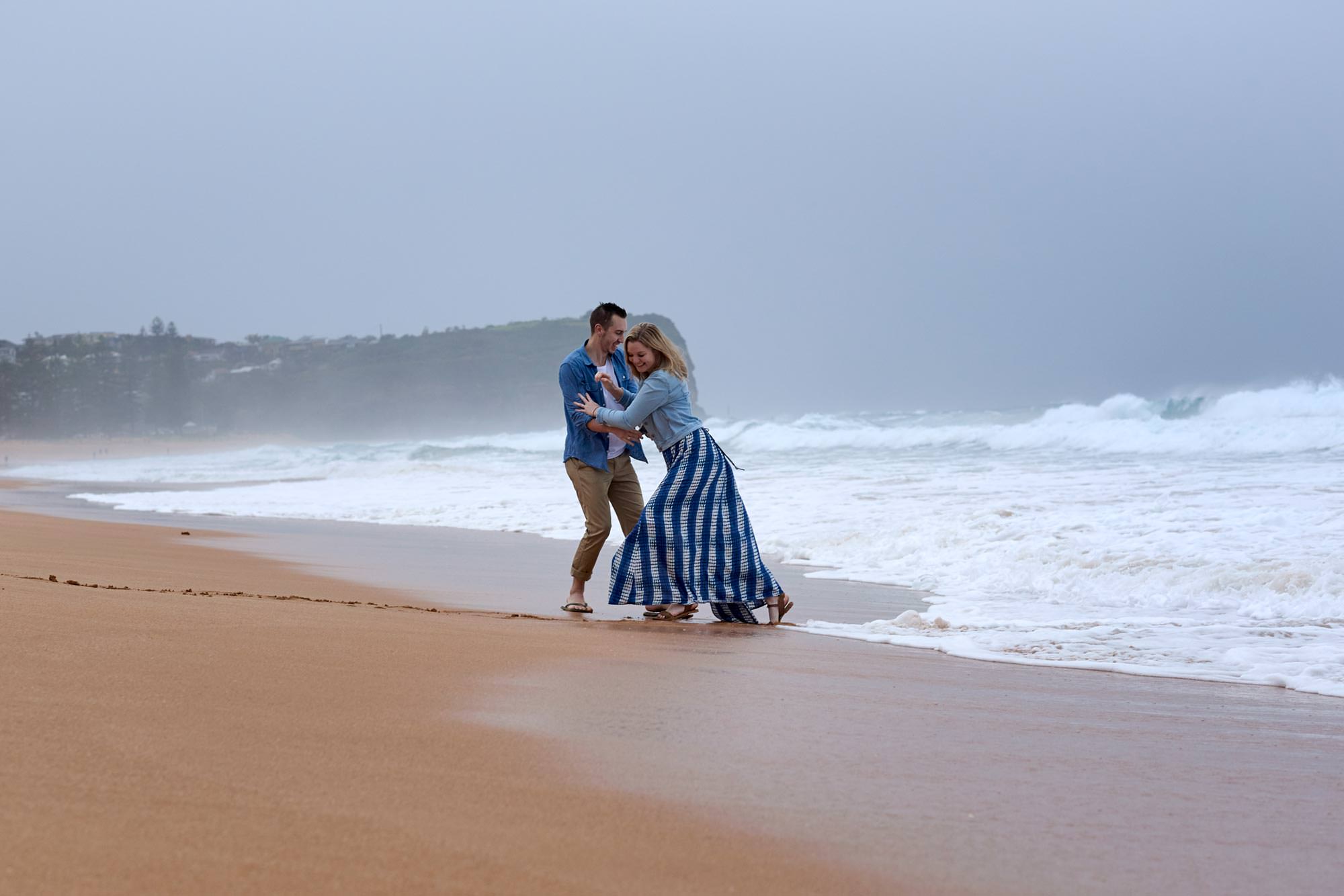 Chris and Bec having fun on Mona Vale Beach in their engagement session